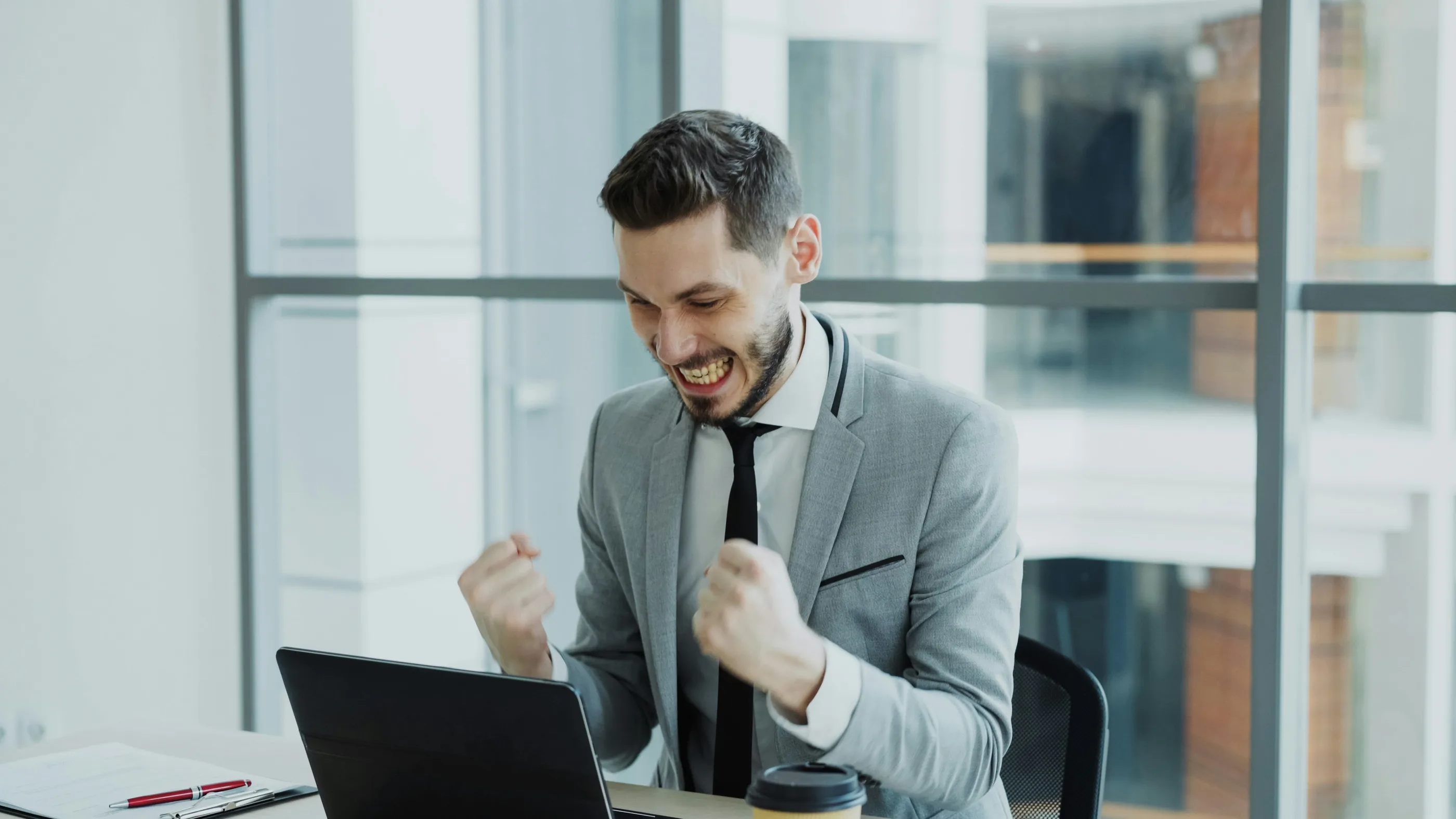 A man celebrating at his laptop